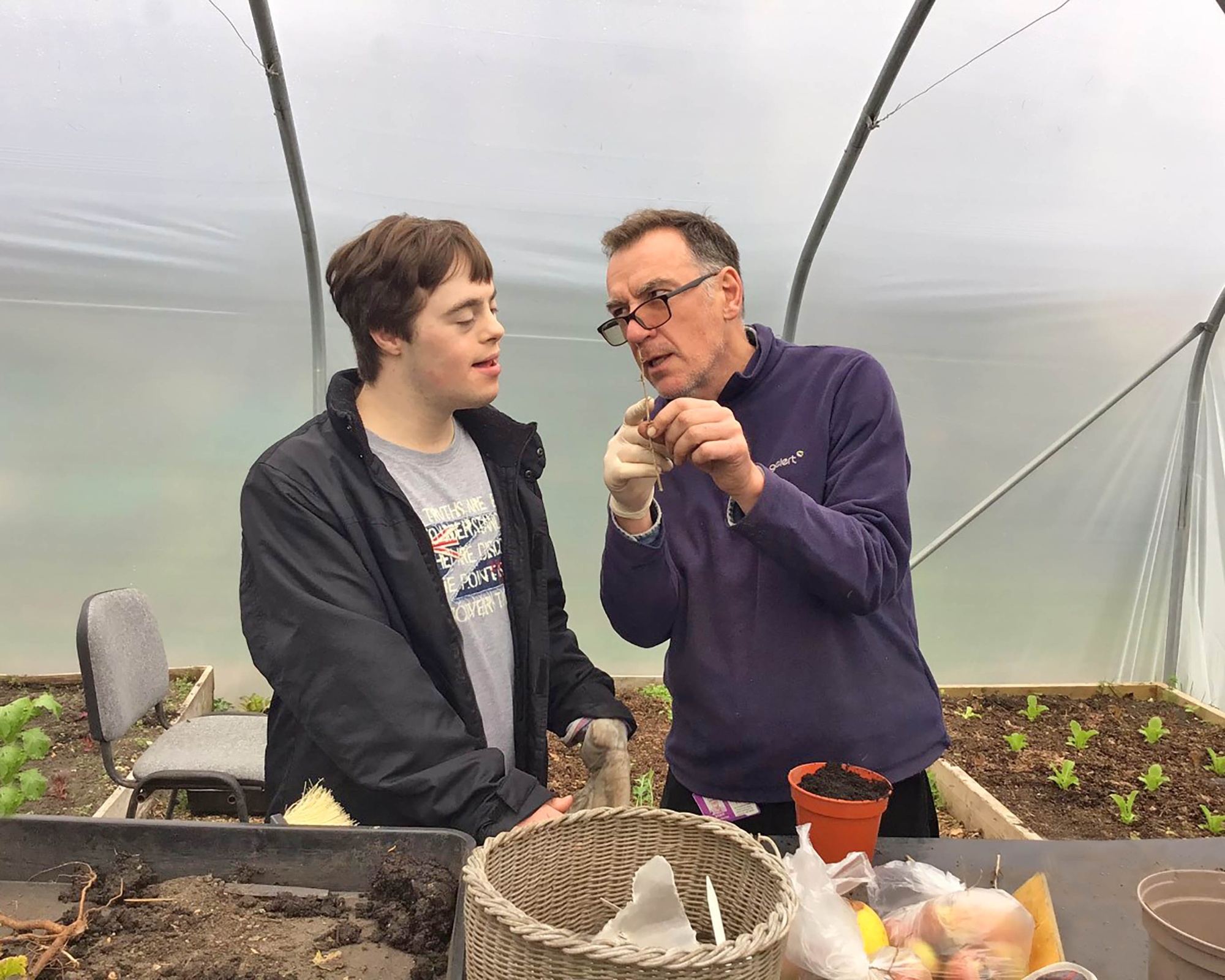 student and teacher inside polytunnel planting at potting table