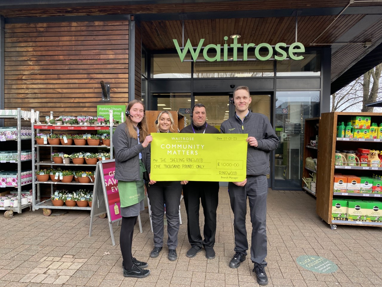 four staff from waitrose supermarket holding up giant cheque